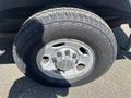A close-up of a silver wheel of a 2012 Chevrolet Express featuring a Chevrolet logo in the center and a rugged tire tread design