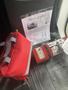 A red fire extinguisher and a red bag are placed on a black surface next to a document about a 2018 Chevrolet Express G4500 27 Passenger Accessibly Wynde