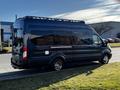 A black 2017 Ford Transit van with a roof rack parked on the side of a road