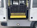 A 2016 Chevrolet Express with a wheelchair lift in the lowered position showing a textured metal surface and a bright yellow edge