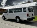 A white 2004 Ford Econoline van parked on a road featuring a sliding side door and a rear that displays large windows and a simple design