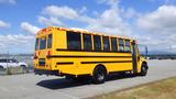 A 2014 Freightliner Thomas Diesel school bus with a bright yellow exterior and black stripes parked in a lot