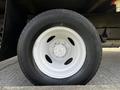 A close-up view of a white steel wheel with a black tire mounted on a 2013 Ford Econoline