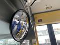 Interior view of a 2018 Chevrolet Express bus featuring a round mirror reflecting empty blue seats and a yellow support pole