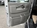 The interior door panel of a 2021 Chevrolet Express with a gray finish featuring a door handle armrest and storage compartments