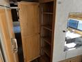 Interior of a 2000 Ford Motorhome showing an open wooden cabinet with shelves and a small mirror reflecting light