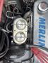 A close-up of a 1970 Chevrolet Corvette engine showcasing a silver aluminum intake manifold and a dual carburetor setup with wiring and hoses visible