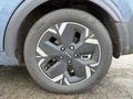 A close-up of a black alloy wheel with a modern design and a Kia logo on a 2023 Kia Niro EV showcasing its unique wheel pattern and tire tread