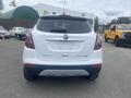 A white 2018 Buick Encore viewed from the rear with the logo prominently displayed on the back hatch and no visible license plate