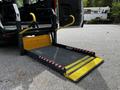 A 2022 Ford Transit with an accessible ramp deployed featuring yellow handrails and safety markings on the edges