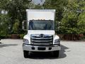 A 2020 Hino 338 box truck with a white cargo area and chrome grille parked with an unobstructed front view