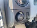 A circular dial with various settings for lights and an adjacent button on the dashboard of a 2014 Ford F-250 SD