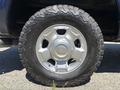 A close-up of a 2014 Ford F-250 SD wheel featuring a silver alloy rim and an aggressive all-terrain tire with a tread pattern designed for off-road performance