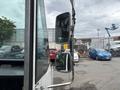 A 2018 Ford Econoline with a side mirror visible in the foreground reflecting parked vehicles and a partly cloudy sky