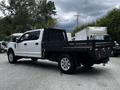 A 2020 Ford F-350 SD with a flatbed truck design featuring a black metal bed and chrome wheels parked at an industrial area