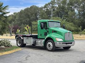 A green 2013 Kenworth T370 flatbed truck is parked with its cab facing forward and a flatbed at the rear for transporting cargo