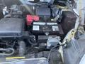 A close-up view of the engine bay of a 2019 Nissan NV200 showing the battery and various engine components