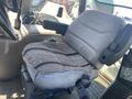 A worn driver's seat from a 2008 Case Super 580M tractor with a patterned seat cover and armrest