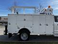 A 2018 Ford F-550 with a white utility body featuring multiple compartments and a ladder rack on the top