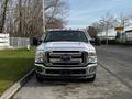 A 2016 Ford F-350 Super Duty truck with a silver exterior and orange roof lights parked on a street