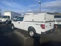 A white 2013 Ford F-150 pickup truck with a utility bed and storage compartments on top parked at a lot