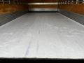 A white 2022 Isuzu NPR truck with a spacious empty cargo area featuring smooth wooden planks and metallic walls