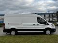 A white 2020 Ford Transit van with a high top and sliding side door parked on grass with a black stripe along the lower body