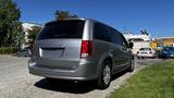 A silver 2016 Dodge Grand Caravan parked with its rear facing the viewer showcasing its sleek design and spaciousness