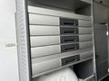 A set of six metallic storage drawers with black handles arranged in a vertical stack inside a vehicle