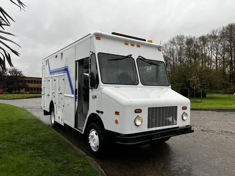 A 2005 Workhorse W-Series delivery truck with a white exterior and blue stripes parked with its side door open