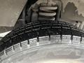 Close-up of a black tire with deep treads mounted on a 2012 Ford Econoline showing slight wear and dirt on the surface