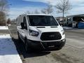 A white 2018 Ford Transit van parked on a snowy street with a black front grille and tinted windows