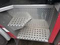 A diamond plate metal step on a fire truck with textured grip surfaces and a small platform on the side