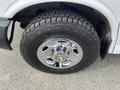 Close-up of a chrome wheel with a rugged tire on a 2012 GMC Savana showcasing its shiny surface and deep tread patterns