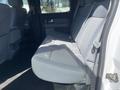 A gray cloth back seat of a 2012 Ford F-150 with seatbelt and armrest features