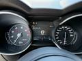 The dashboard of a 2020 Alfa Romeo Stelvio featuring a speedometer odometer and digital display showing the time temperature and vehicle speed