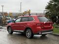 A 2016 Mitsubishi Outlander in red with a sleek design featuring roof rails and alloy wheels parked at an angle