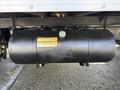 Underneath a 2014 Hino 195 is a round black fuel tank with a yellow warning label and a gauge on top attached to a metal frame
