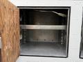 A metal storage compartment with a wooden door slightly open revealing an empty interior and a visible metal shelf inside
