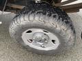A close-up of a rugged tire mounted on a silver rim with a Ford logo showing deep treads designed for off-road traction on a 2005 Ford F-350 SD