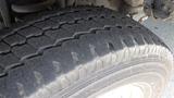 Close-up of a worn tire from a 2011 Ford Econoline showing the tread patterns and sidewall details