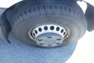 A close-up of the wheel and tire of a 2012 Mercedes-Benz Sprinter featuring a silver wheel rim and a black tire with a tread pattern