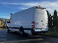 A white 2008 Dodge Sprinter Van with a high roof and a star decoration on top is parked with its rear facing the viewer