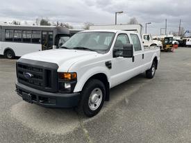 A white 2010 Ford F-250 Super Duty pickup truck parked in a lot with a black grille and headlights