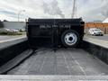 A 2021 Ford F-550 truck bed featuring a black liner supported by a metal frame with a spare tire positioned against the back wall