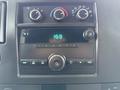 Dashboard of a 2014 GMC Savana featuring climate control knobs a digital clock and a radio with various buttons and an auxiliary input