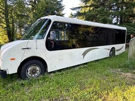 2005 Workhorse Glaval LF72 bus designed for 21 passengers with a white exterior and black tinted windows parked on grass