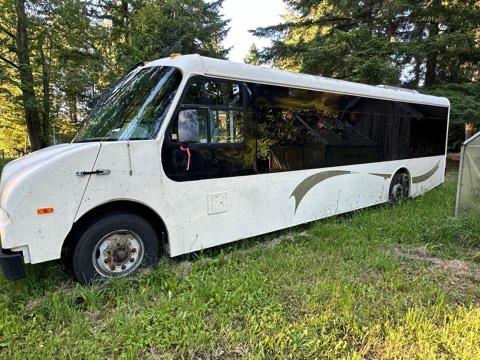 2005 Workhorse Glaval LF72 bus designed for 21 passengers with a white exterior and black tinted windows parked on grass