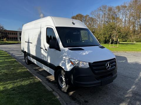 A 2022 Mercedes-Benz Sprinter van with a white body and black accents parked on the side of the road