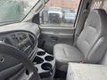 Interior view of a 2008 Ford Econoline showing a gray driver's seat and a dashboard with controls and a cup holder console